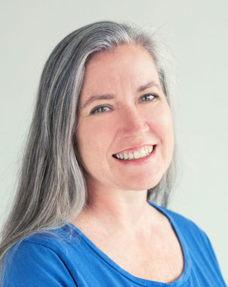 Susan Wright has long silver-grey hair, blue eyes, and a warm smile.