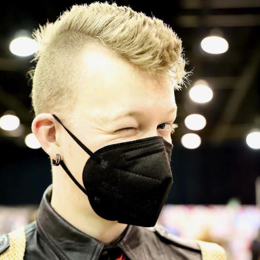 Jake is a white non-binary young adult with a short mohawk, wearing a mask